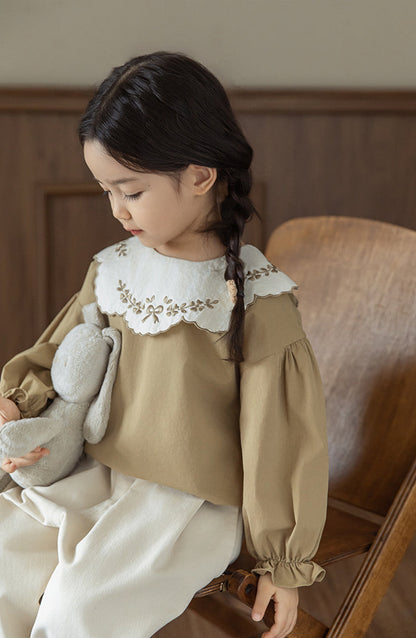 Girls wearinga akhaki cotton blouse with embroidered collar