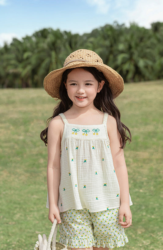 Young girl in a muslin cotton summer top and straw hat standing in a grassy field 