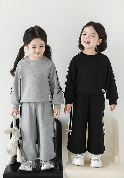 Girls wearing grey sweatshirt and joggers set with ribbon detailing