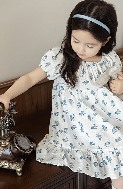 Girl wearing summer blue floral dress with square neck and puffed sleeves