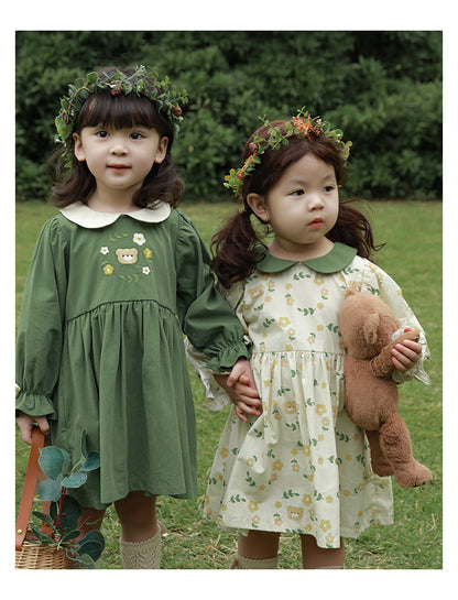 Girls in dresses with floral crowns standing outdoors.